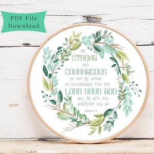 Könnte beinhalten: Ein weißer Stickrahmen mit einem grünen floralen Kranzdesign. Der Kranz umgibt ein Zitat aus der Bibel: "Seid stark und mutig. Fürchtet euch nicht und verzweifelt nicht, denn der Herr, euer Gott, ist mit euch, wohin ihr auch geht. Josua 1,9."