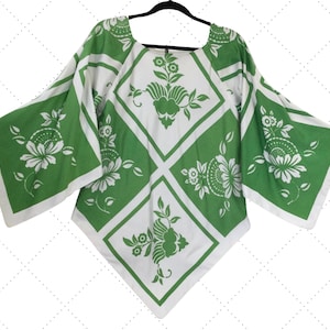 May include: A white and green patterned blouse with a diamond pattern and floral designs. The blouse has a wide, loose fit and a scoop neckline.