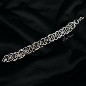 Pode incluir: Uma pulseira de malha de corrente prateada com uma s&eacute;rie de an&eacute;is interligados. A pulseira &eacute; exibida em um fundo preto. O texto "Velvet Vixen" &eacute; vis&iacute;vel na pulseira.