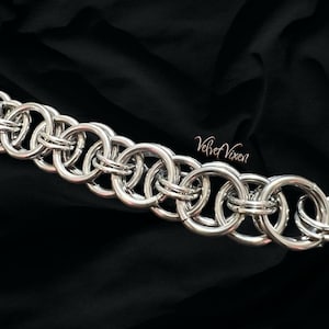 Pode incluir: Uma pulseira de malha de corrente prateada com um padr&atilde;o repetitivo de an&eacute;is interligados. A pulseira &eacute; exibida contra um fundo preto. O texto "Velvet Vixen" est&aacute; no canto inferior direito.
