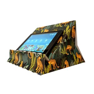 May include: A cardboard tablet stand with a jungle print featuring leopards and green foliage. The stand is folded up with a tablet resting on top.