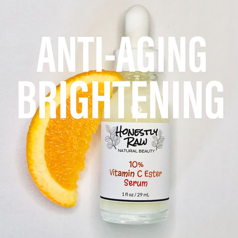 May include: A clear glass bottle with a white dropper top and a white label. The label says "Honestly Raw Natural Beauty 10% Vitamin C Ester Serum 1 fl oz/29 mL". The bottle is sitting on a white surface with a slice of orange next to it. The text "ANTI-AGING BRIGHTENING" is written in large white letters above the bottle.
