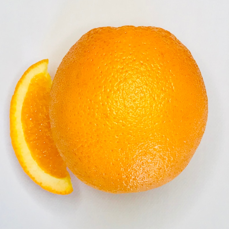 May include: A whole orange and a slice of orange on a white background. The orange is bright yellow and has a rough texture. The slice is also bright yellow and has a smooth texture.