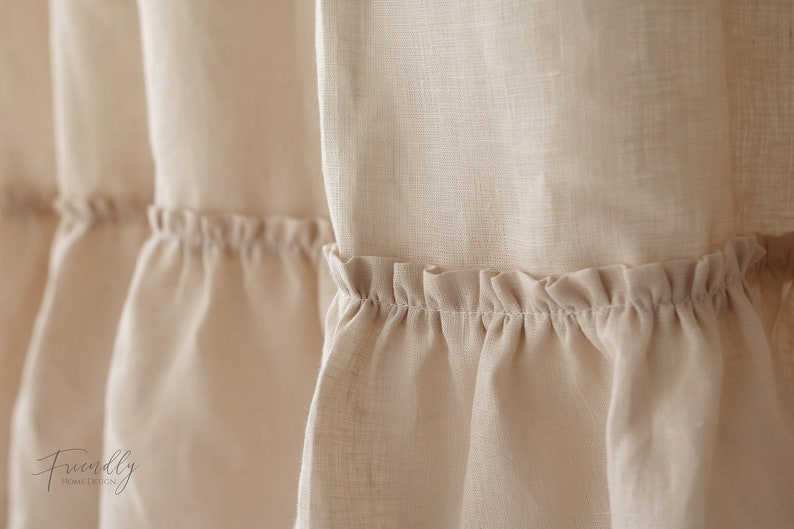 Puede incluir: Primer plano de una cortina de lino beige con un dobladillo con volantes. La tela es suave y texturizada, creando un aspecto delicado y rom&aacute;ntico.