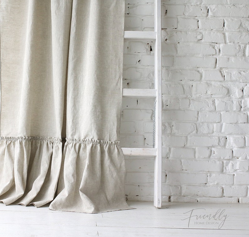 Puede incluir: Un par de cortinas de lino beige con un borde inferior con volantes. Las cortinas est&aacute;n colgadas frente a una pared de ladrillo blanco y una escalera blanca.
