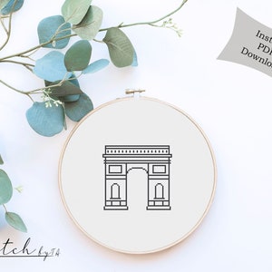 Pode incluir: Um padrão de ponto cruz preto e branco do Arco do Triunfo em Paris, França. O padrão está sobre um fundo branco e está emoldurado em um aro de bordado redondo.