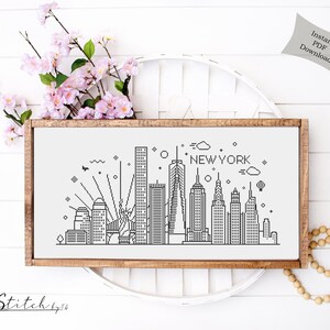May include: A black and white line art cross stitch pattern of the New York City skyline. The pattern includes the Empire State Building, the Chrysler Building, and the Freedom Tower. The text "NEW YORK" is written above the skyline.