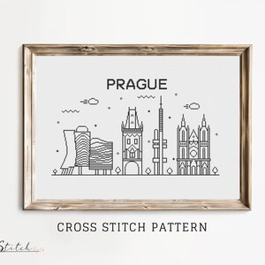 May include: Black and white cross stitch pattern of the Prague skyline, featuring iconic buildings like the Old Town Square and the Charles Bridge. The pattern includes the word "PRAGUE" at the top.