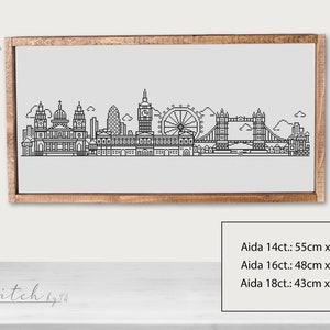 May include: Black and white line art illustration of the London skyline, including Big Ben, the London Eye, and Tower Bridge. The image is framed in a light brown wood frame. The text "Aida 14ct.: 55cm x 13cm, Aida 16ct.: 48cm x 11cm, Aida 18ct.: 43cm x 10cm" is printed below the image.