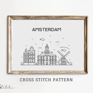 May include: Black and white line art cross stitch pattern of the Amsterdam skyline, featuring a windmill, buildings, and the text "AMSTERDAM" and "CROSS STITCH PATTERN".