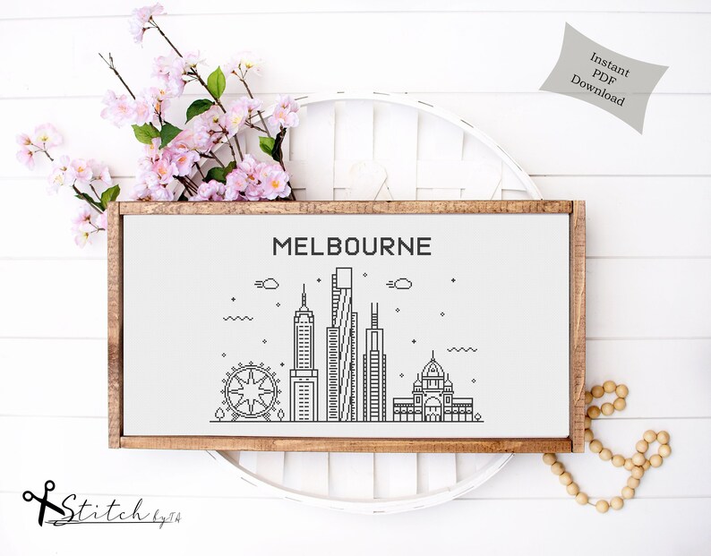 May include: A black and white line art illustration of the Melbourne skyline, including the Melbourne Star Observation Wheel, Federation Square, and other iconic buildings. The illustration is framed in a light brown wood frame and is set against a white background.