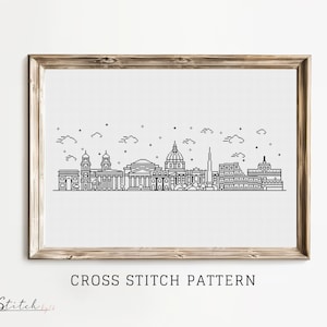 Puede incluir: Patrón de punto de cruz en blanco y negro de la línea del horizonte de Roma, con el Coliseo, el Panteón y la Basílica de San Pedro. El patrón está enmarcado en un marco de madera claro y el texto "CROSS STITCH PATTERN" está debajo de la imagen.