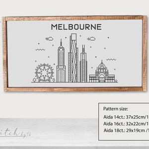 May include: A black and white line art illustration of the Melbourne skyline, including the Melbourne Star Observation Wheel, Federation Square, and several skyscrapers. The illustration is framed in a light brown wood frame and is labeled "MELBOURNE". The text "Pattern size:" is below the image, followed by the dimensions of the pattern in inches and centimeters for Aida 14ct, 16ct, and 18ct.