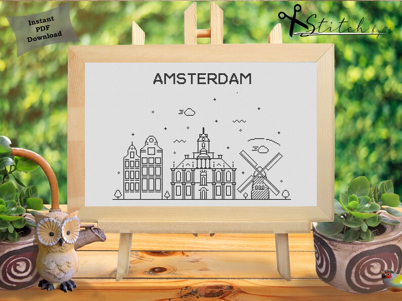 May include: Black and white line art illustration of the Amsterdam skyline featuring buildings, a windmill, and the text "AMSTERDAM".
