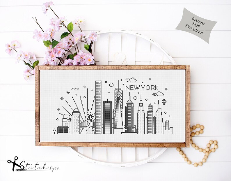 May include: A black and white line art cross stitch pattern of the New York City skyline. The pattern includes the Empire State Building, the Chrysler Building, and the Freedom Tower. The text "NEW YORK" is written above the skyline.