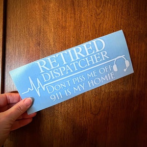 May include: A blue and white sticker with the text "Retired Dispatcher Don't piss me off 911 is my homie" and a stylized heartbeat graphic. The sticker also features a white headset graphic.