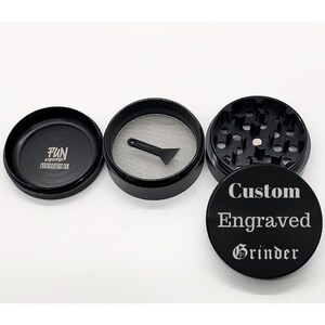 Puede incluir: Triturador de metal negro con un mensaje grabado personalizado que dice "Custom Engraved Grinder". El triturador tiene una tapa de metal negro con el texto "FUN engravings FUNengravings.com" impreso en ella.