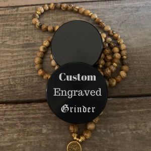 Puede incluir: Molino redondo negro con el texto "Custom Engraved Grinder" en letras blancas.