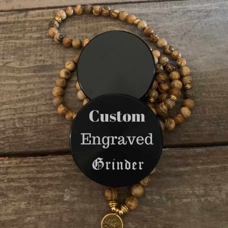 Puede incluir: Molino redondo negro con el texto "Custom Engraved Grinder" en letras blancas.