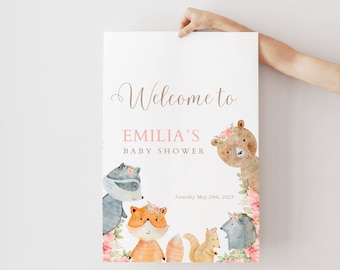 May include: Welcome to Emilia's Baby Shower sign with a watercolor illustration of woodland animals including a fox, raccoon, squirrel, hedgehog, and bear. The animals are surrounded by pink flowers.