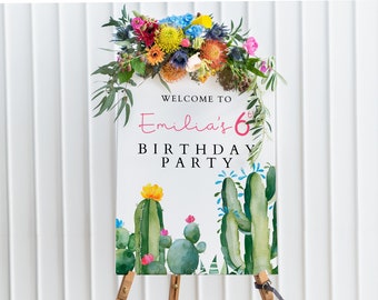 May include: Welcome to Emilia's 6th Birthday Party sign with a watercolor cactus design. The sign is white with pink text and is decorated with a floral arrangement.