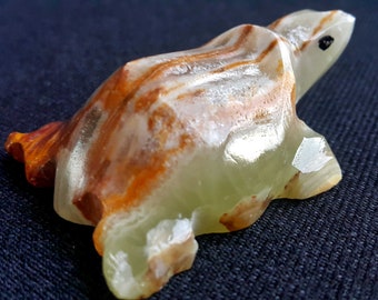 May include: A carved stone turtle figurine. The turtle is primarily light green with brown and orange veining. The turtle's eye is a small black dot. The figurine is a decorative item.