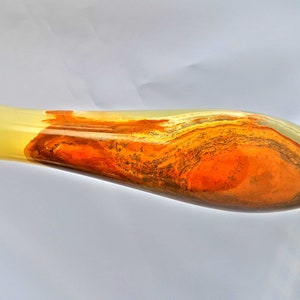 Pu&ograve; includere: Un vaso lungo e sottile in onice con una base giallo chiaro e un motivo a spirale di arancione, marrone e grigio.