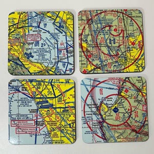 May include: Set of four square coasters featuring detailed aviation charts of California cities. Each coaster displays a different area, including Sacramento, San Francisco, Los Angeles, and Monterey, with various airport information.