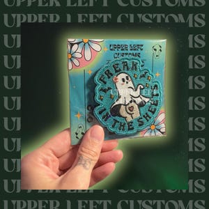 May include: A teal embroidered patch with the text "Freak in the Sheets" surrounding a cartoon ghost. The patch is on a teal card with daisy and skull graphics. The brand name "Upper Left Customs" is printed on the card.