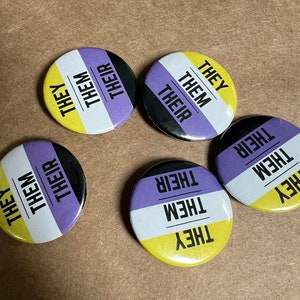 May include: Five round buttons with the words "They", "Them", and "Their" in black and white text on a yellow, black, and purple background.