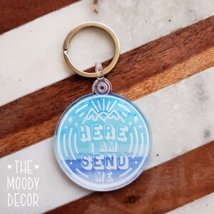 Könnte beinhalten: Ein blauer und weißer Schlüsselanhänger im Aquarell-Stil mit dem Text "Here I Am Send Me" und einer Bergkette. Der Schlüsselanhänger ist an einem silbernen Schlüsselring befestigt.