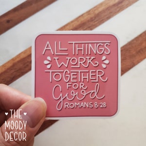 May include: Pink sticker with the text "All things work together for good Romans 8:28" in white lettering.