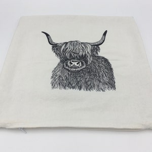May include: A white pillowcase with a black and white line drawing of a Highland cow with long horns and a fluffy mane.