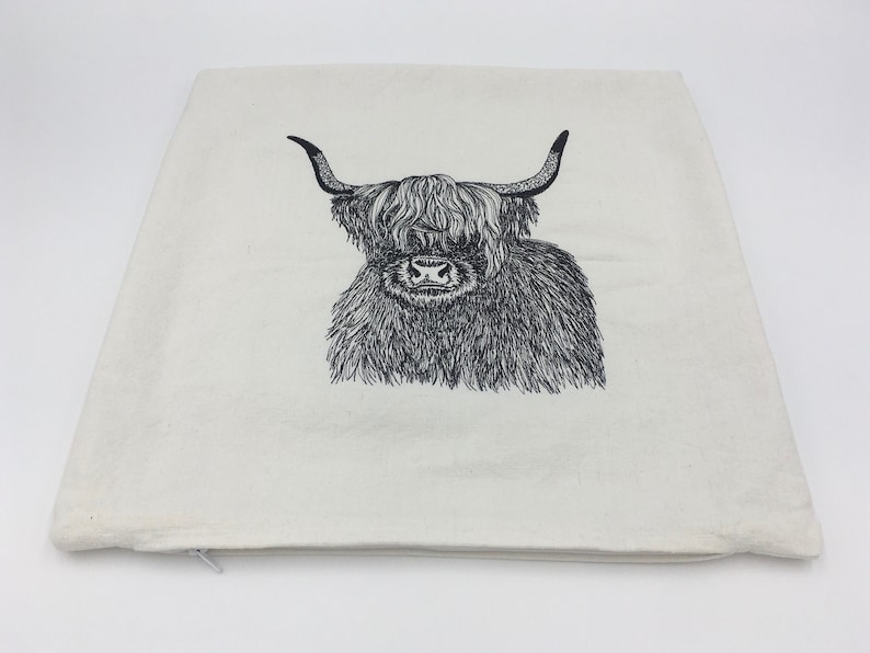 May include: A white pillowcase with a black and white line drawing of a Highland cow with long horns and a fluffy mane.