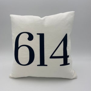 May include: White pillow with the number 614 embroidered in black.