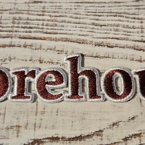May include: A red and white embroidered patch with the word "Morehouse" in a bold, serif font.