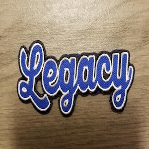 May include: Blue and white embroidered patch with the word "Legacy" in a cursive font.