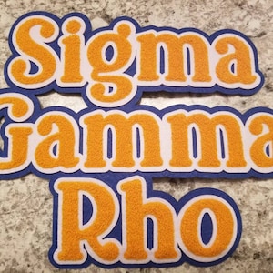 May include: Orange felt letters spelling "Sigma Gamma Rho" on a blue background.