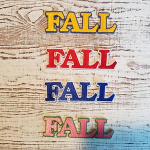 Peut inclure: Quatre patchs en feutre avec le mot "FALL" en diff&eacute;rentes couleurs : jaune, rouge, bleu et rose.