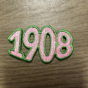 May include: A pink and green embroidered patch with the number 1908.