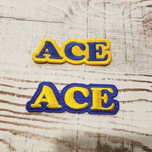 May include: Two yellow felt patches with blue embroidered letters spelling "ACE".