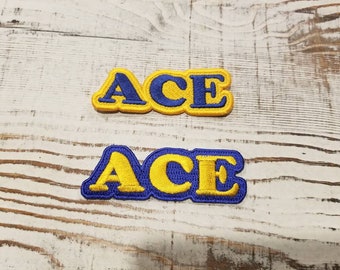 May include: Two yellow felt patches with blue embroidered letters spelling "ACE".