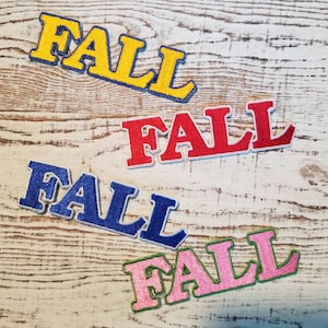 May include: Four felt patches spelling out the word "FALL" in different colours: yellow, red, blue, and pink.
