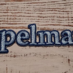 May include: Blue embroidered patch with the name "Spelman" in a bold, blocky font.