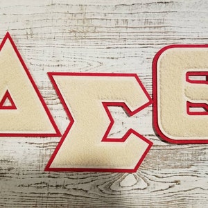 May include: Three white felt letters with red outlines, spelling out "A". "Σ", and "Θ".