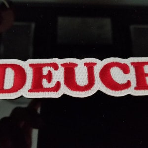 May include: Red embroidered patch with the word "DEUCE" in white outlined letters.