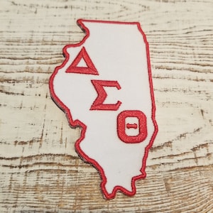 Op de afbeelding: Rode geborduurde patch in de vorm van de staat Illinois met de letters Delta Sigma Theta.