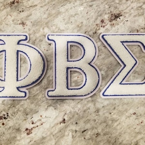 May include: White felt letters with blue outlines spelling out "ΦΒΣ".