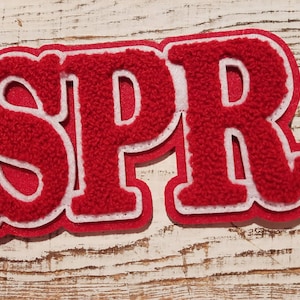 May include: Red felt letter patch with white outline spelling "SPR".
