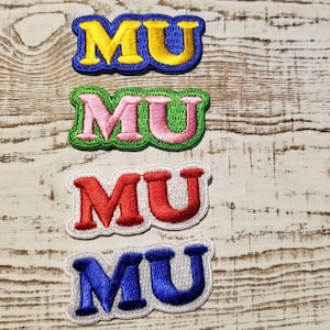May include: Four embroidered iron-on patches with the letters "MU" in different colours: yellow, pink, red, and blue.